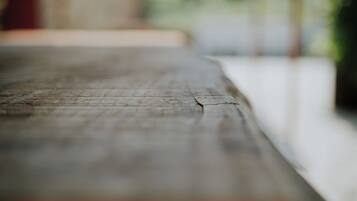 A wooden bench with a slatted seat and backrest, positioned outdoors with a blurred background suggesting a natural setting.