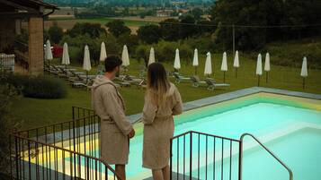 Un espace piscine avec des marches descendant vers l’eau, entouré de chaises longues et de parasols.