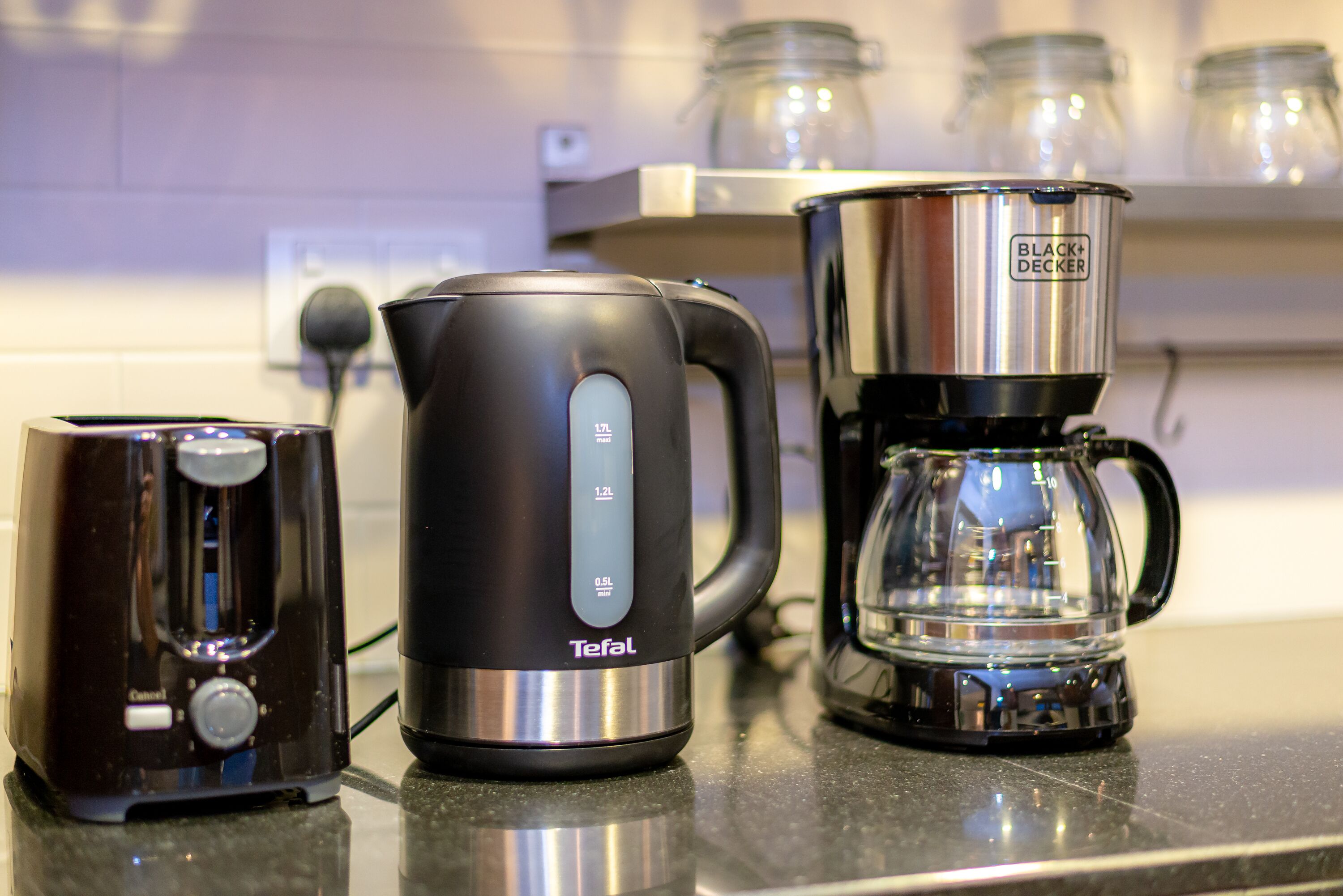 Un plan de travail de cuisine avec une machine à café, une bouilloire et une cafetière.