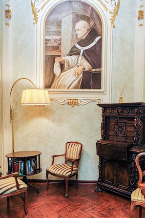 A room with a framed portrait, a lamp, a chair, and a wooden cabinet. - Dimora del Cardinale - Residenza d'epoca (Florence)