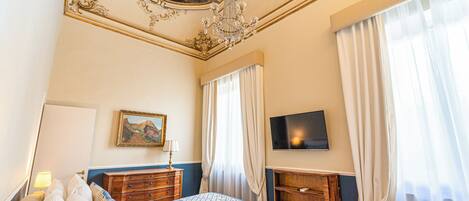 Een hotelkamer met een bed, een televisie, een schilderij en een pronkstuk.