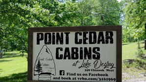 A sign for Point Cedar Cabins at Lake Degrey, including a Facebook link and a website for booking.