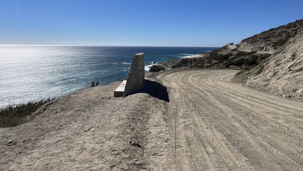 Una carretera costera con un monumento de piedra que lleva a una playa.