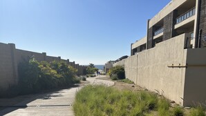Un camino bordeado por muros de concreto y vegetación verde, que lleva a un edificio de diseño moderno.