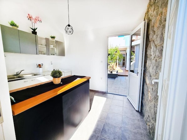 Una cocina moderna con encimera negra, armarios blancos y pared de piedra.