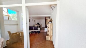 Un amplio espacio de sala con un sofá, una mesa de comedor y una silla de mimbre.