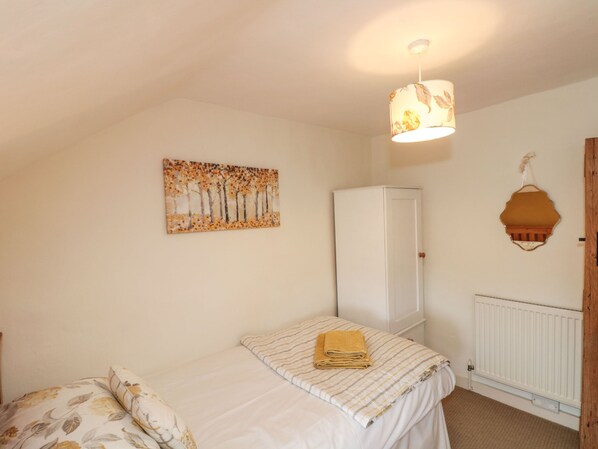 A bedroom with a bed, a wardrobe, a radiator, and a painting on the wall. - 12 Castlegate (Pickering)