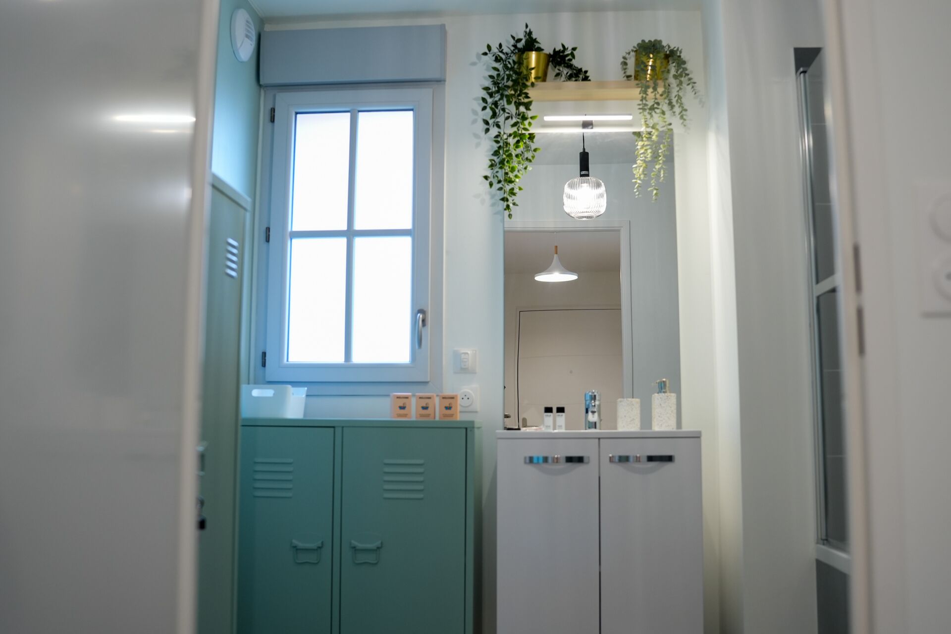Une salle de bain avec une fenêtre, un miroir, un lavabo et des placards.