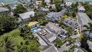 An aerial view of a coastal residential area with houses, a swimming pool, and boats on the water.