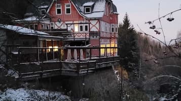 Ein großes, mehrstöckiges Gebäude mit Balkon, umgeben von verschneiter Landschaft und Bäumen.
