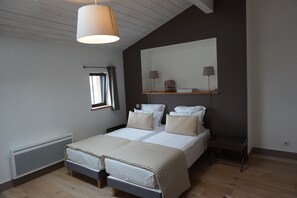 A bedroom with two beds, a large mirror, bedside lamps, and a window with curtains.