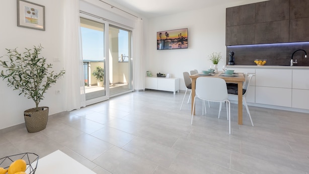 Una cocina moderna con comedor, un ventanal grande y una puerta corredera que da a un balcón.