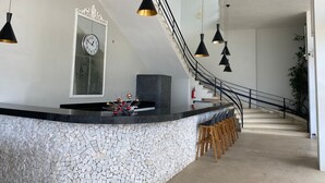 A modern kitchen with a curved island, black pendant lights, a clock, and a staircase leading to another level. - Guarujá Apartment, Building on the Waves, Pitangueiras Beach, Pé na Areia (Guarujá)