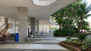 A spacious indoor area with a curved ceiling, a stone pillar, and a tiled floor. - Guarujá Apartment, Building on the Waves, Pitangueiras Beach, Pé na Areia (Guarujá)