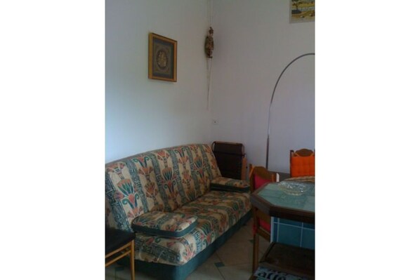 Ein Wohnzimmer mit einem gemusterten Sofa, einem kleinen Tisch und einem Sessel.