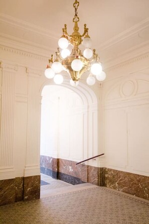 A grand hall with a large chandelier, marble flooring, and classical architecture.