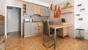 A compact kitchen with a dining area, wooden cabinets, a microwave, a stove, and a hanging light fixture.