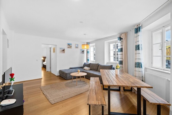 A modern living room with a sofa, wooden tables, and a TV.