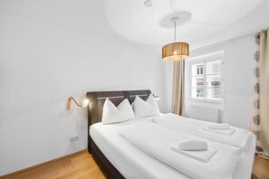 Ein Hotelzimmer mit Bett, einer Hängelampe, einem Fenster mit Vorhängen und Blick auf Gebäude.