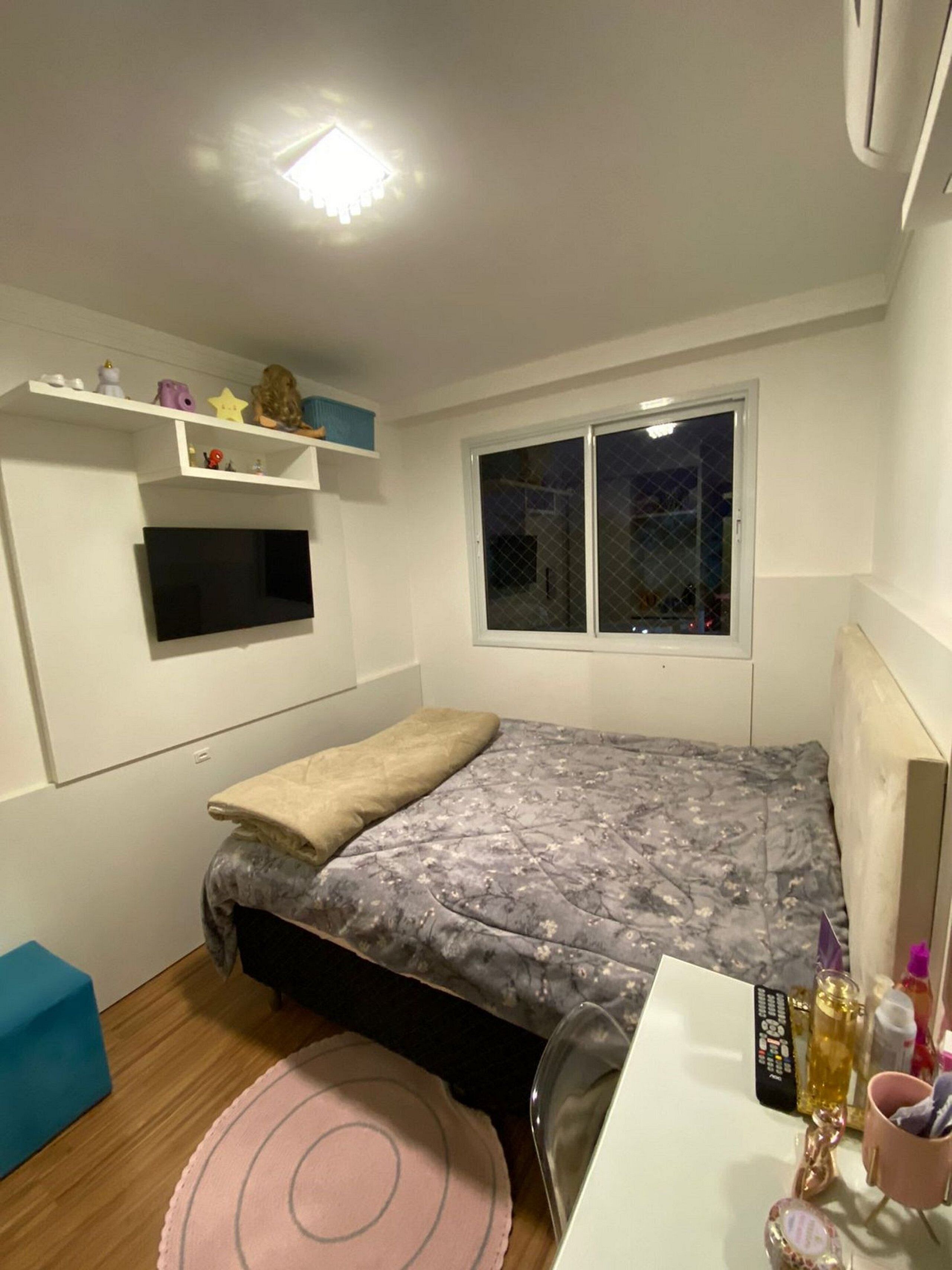 Un dormitorio pequeño y bien iluminado con cama, escritorio y ventana.