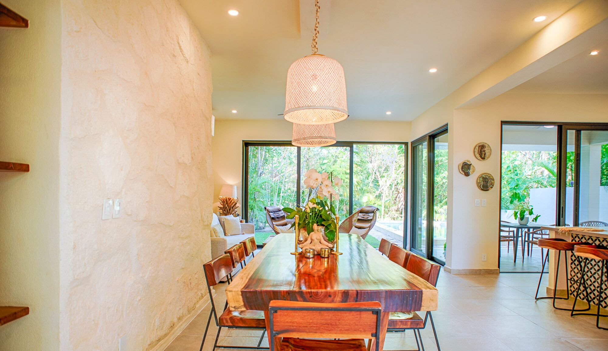 A spacious dining area with a long wooden table, comfortable chairs, and a hanging light fixture.