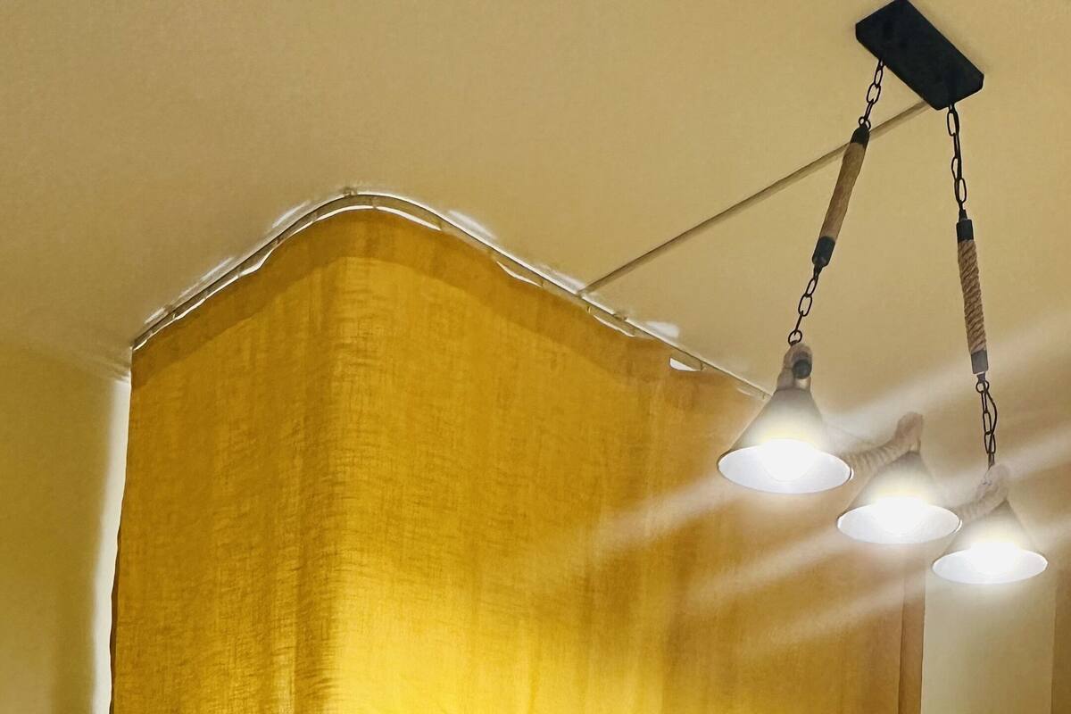 A bunk bed with a yellow canopy and a ladder, in a room with wooden flooring and a hanging light fixture.