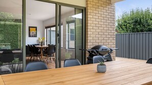 An outdoor dining area with a wooden table and chairs, a motorcycle, and a potted plant.