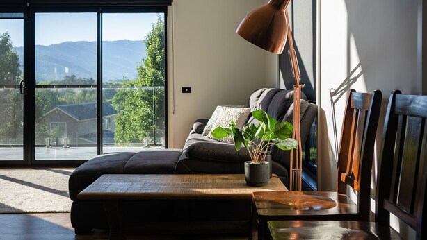 Un salon moderne avec une grande fenêtre, un canapé, une table basse et une lampe.