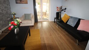 A living room with a sofa, a coffee table, and a vase of flowers. - Harriers Grove House (Sutton-in-Ashfield)