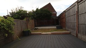 A wooden deck with a brick border, a brick wall, and a metal gate. - Harriers Grove House (Sutton-in-Ashfield)