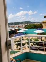 Un balcón con vistas a un pueblo costero, sombrillas de exterior y una zona de piscina.