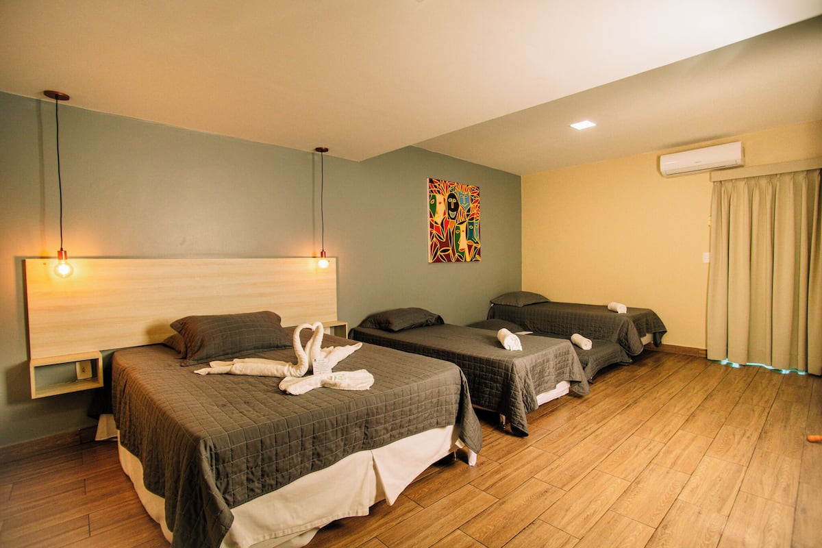 Une chambre d’hôtel avec deux lits, un climatiseur fixé au mur et un tableau.