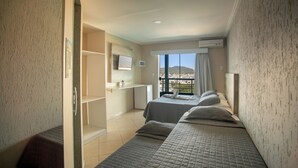 Een hotelkamer met twee bedden, een klein bureau, een televisie en een balkon met uitzicht.