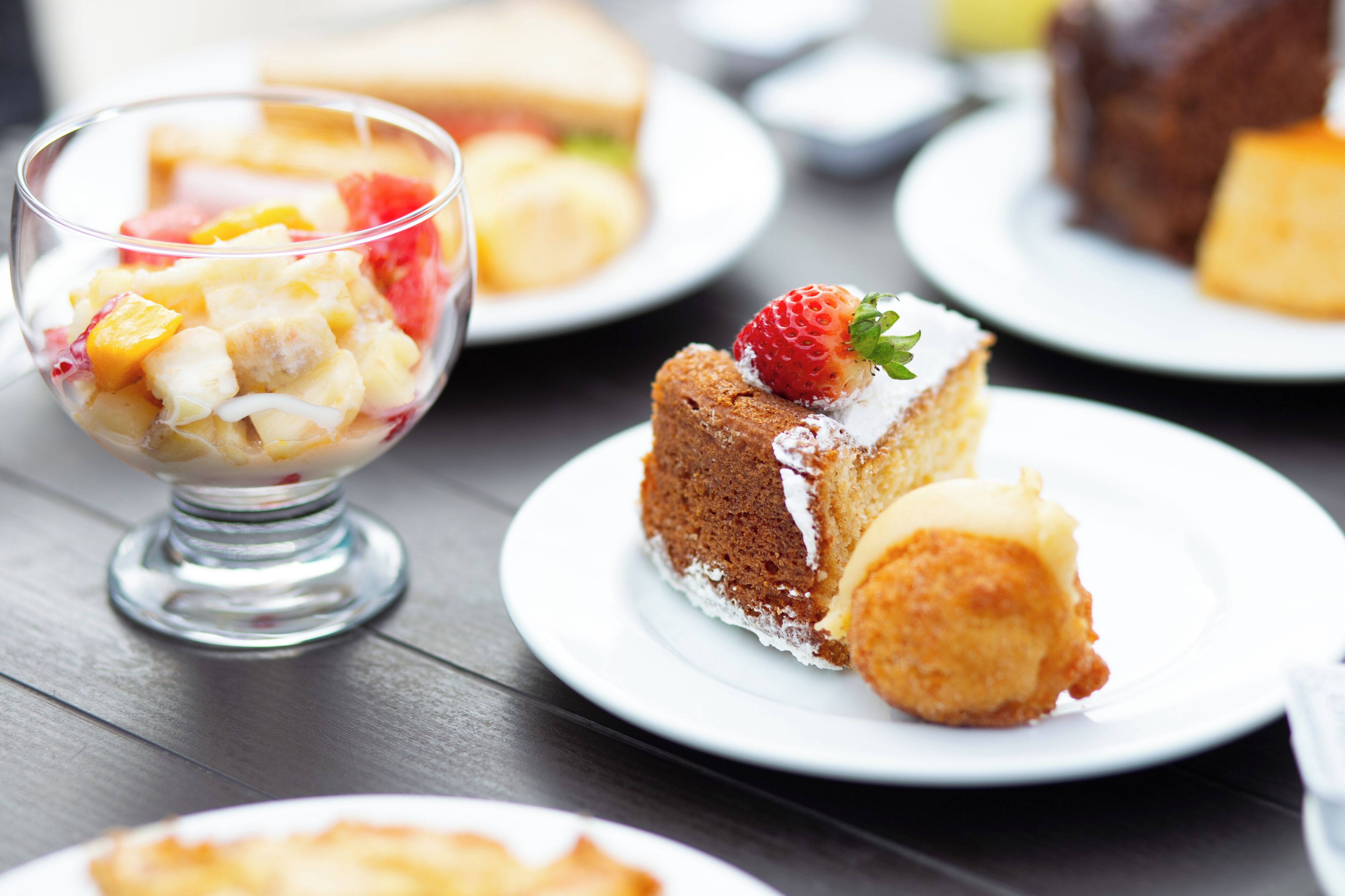A dessert table with various cakes and a fruit salad.