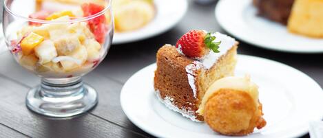 A dessert table with various cakes and a fruit salad.
