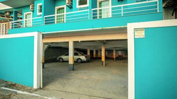 A turquoise building with a covered parking area and a car inside.