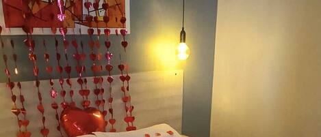 Quarto de hotel com uma cama, uma obra de arte na parede e um adorno pendurado.