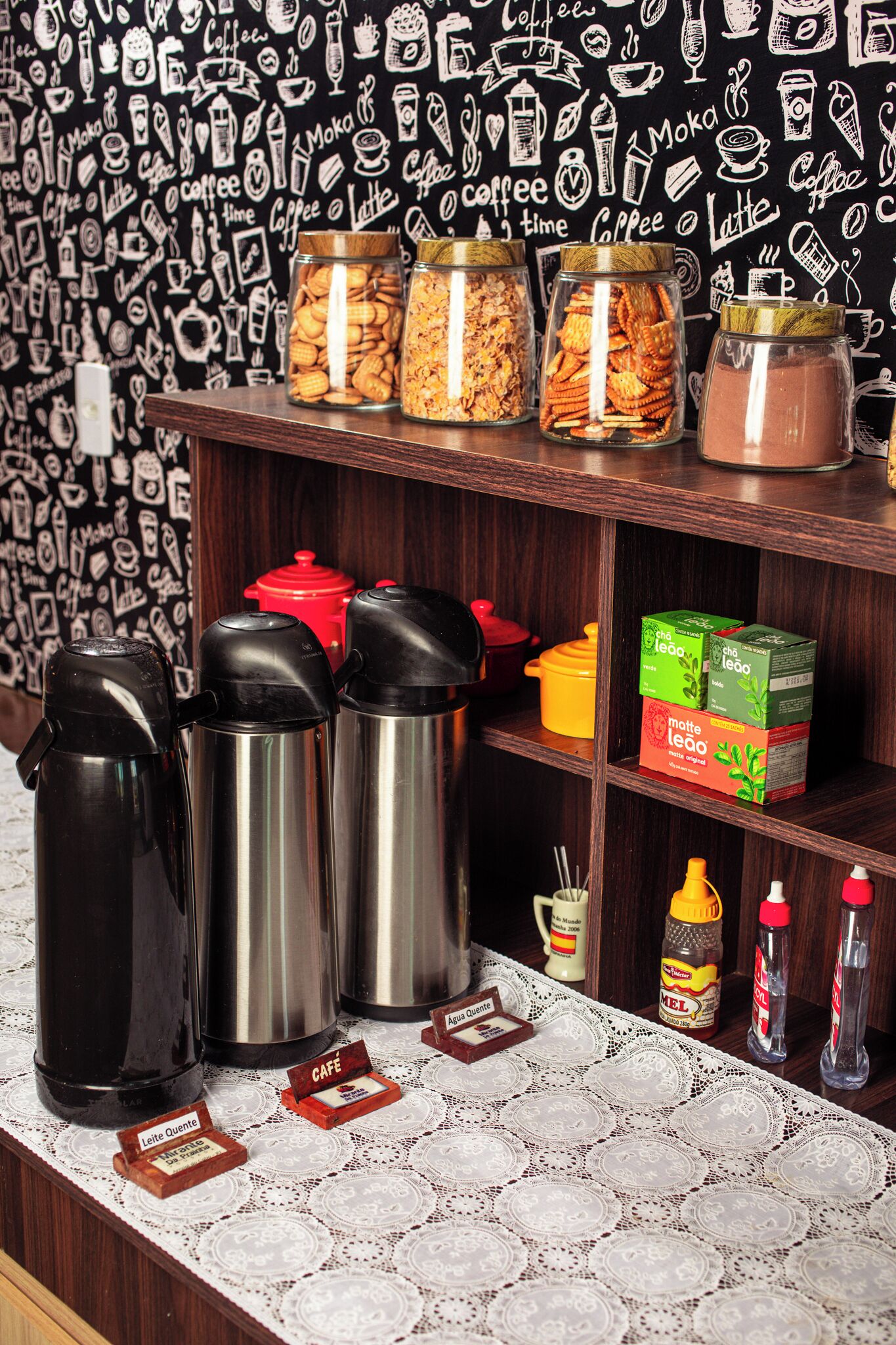 Et tekøkken med kaffemaskine, krukker med snacks og kasser med kaffe.