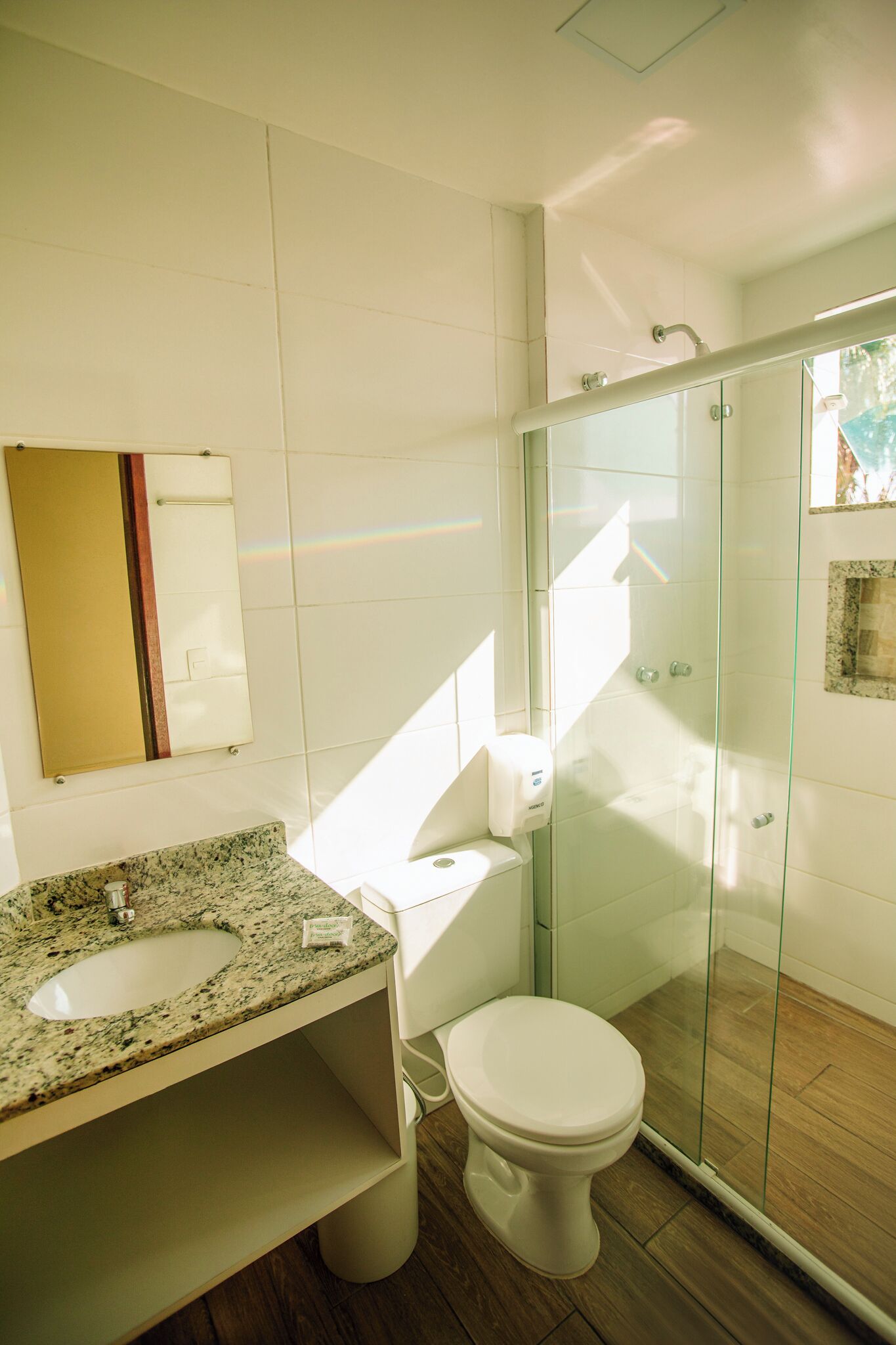 Un baño moderno con lavamanos, inodoro y cabina de ducha de vidrio de granito.