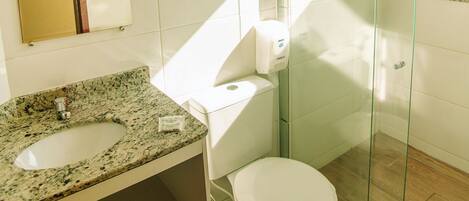 Un baño moderno con lavamanos, inodoro y cabina de ducha de vidrio de granito.