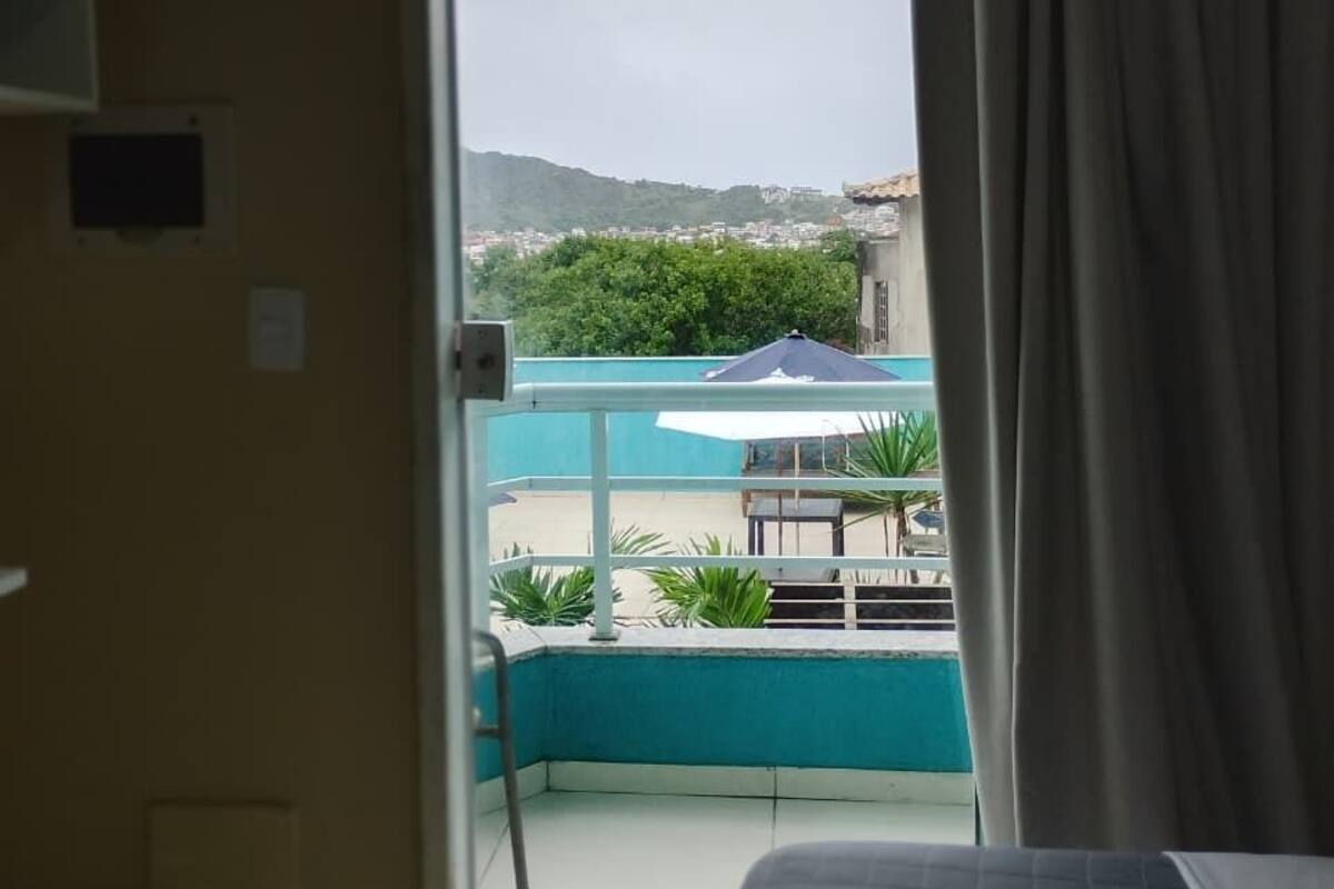 Une chambre avec un lit, une fenêtre avec des rideaux et une vue sur une piscine et la verdure environnante.