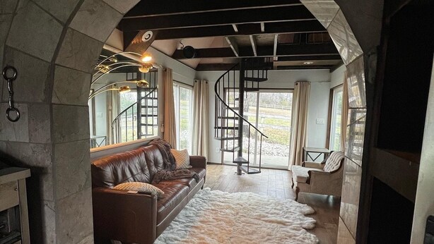 Een gezellige woonkamer met een leren bank, een bont tapijt en een spiltrap.