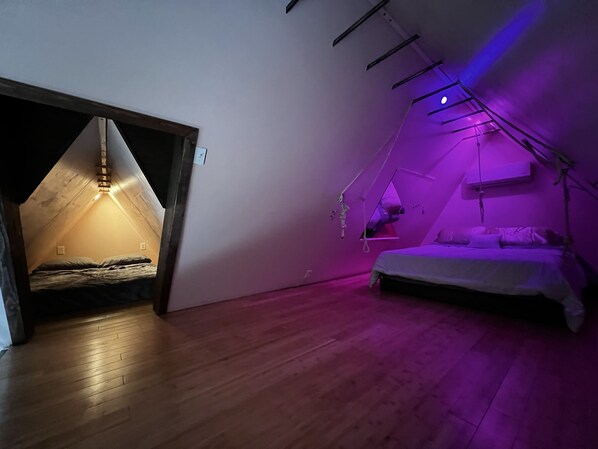 Un dormitorio con techo inclinado, una cama y piso de madera.