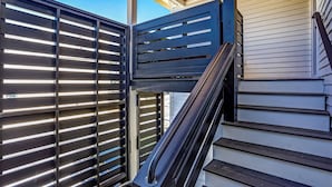 A staircase with a metal railing leading to a covered area with a wooden ceiling.