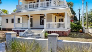 A two-story house with a balcony, a front porch, and a brick foundation.