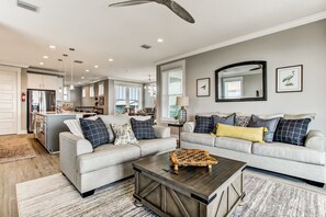 A spacious living area with two sofas, a coffee table, and a kitchen in the background.
