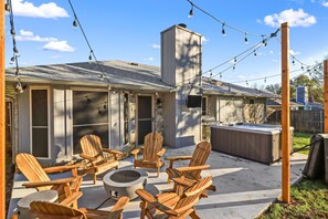 A patio with Adirondack chairs, a fire pit, and a hot tub. - Cozy Updated Home w/ Hot Tub minutes from DFW Airport (Euless)