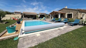 A swimming pool with a slide, lounge chairs, and a stone house in the background. - Villa Rube's (Gordes)