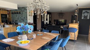 A modern kitchen with a dining area, a chandelier, and a television. - Villa Rube's (Gordes)