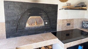 A stone fireplace with a black arch, a mirror, and a shelf with cleaning tools. - Villa Rube's (Gordes)